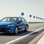 Carro azul trafegando por uma estrada com placas azuis de quilometragem ao fundo, ilustrando deslocamento ao longo do tempo.